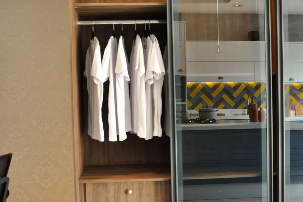 Closet planejado com cabideiro, gaveteiro interno e portas de vidro